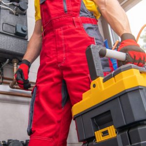 person with red overalls holding toolbox