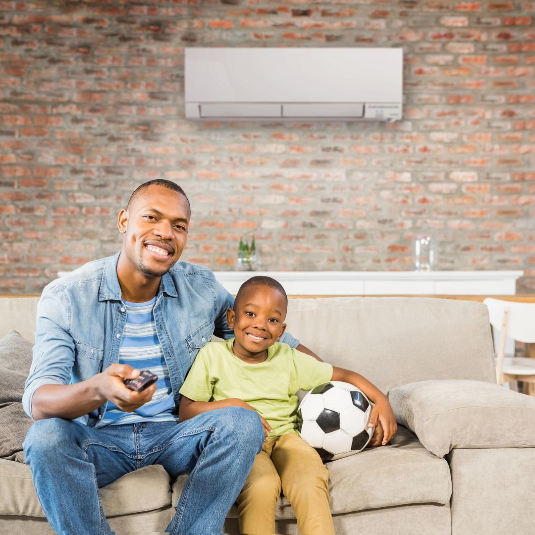 Man sitting next to a young child on a couch, smiling. 