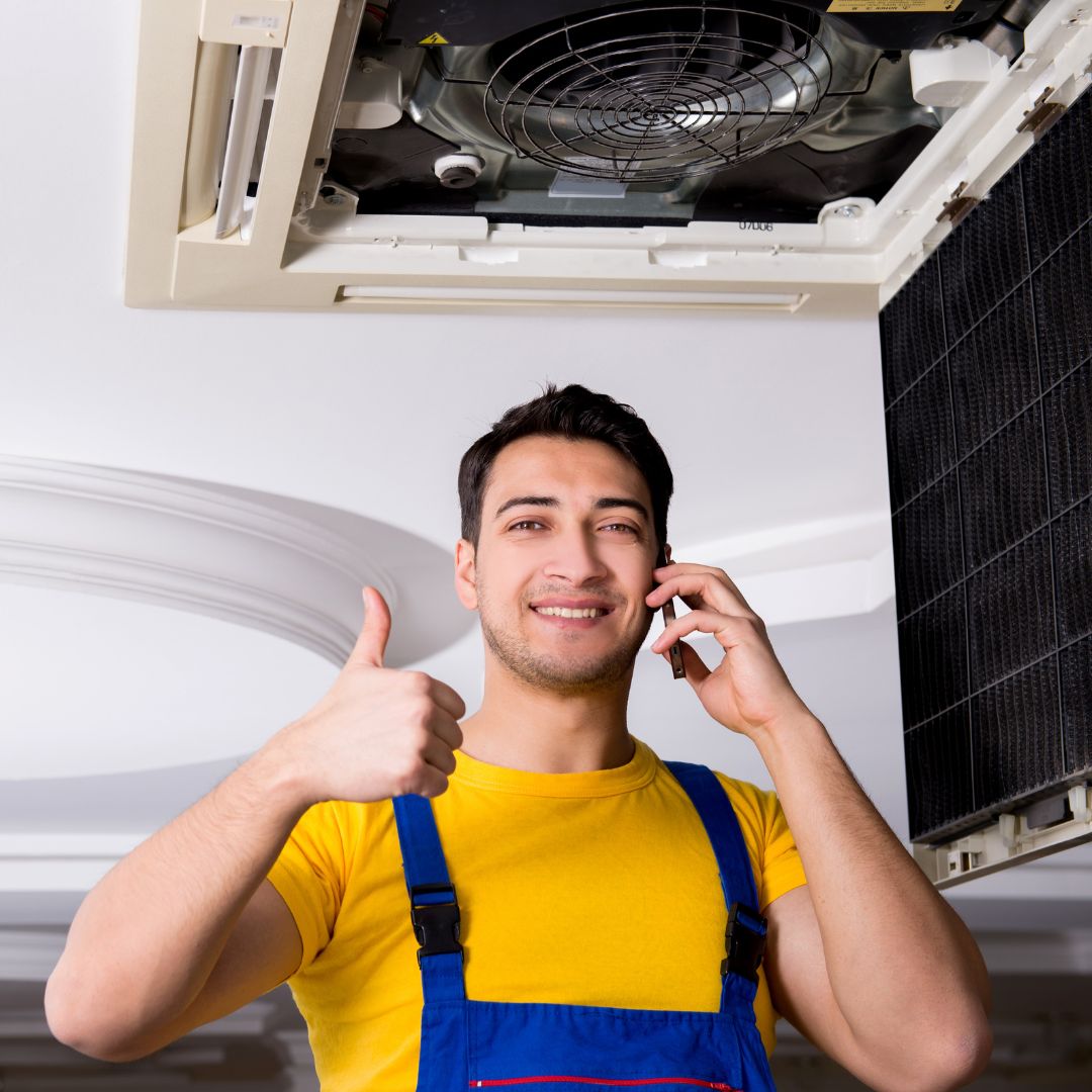 HVAC technician talking on the phone, giving a thumbs up. 