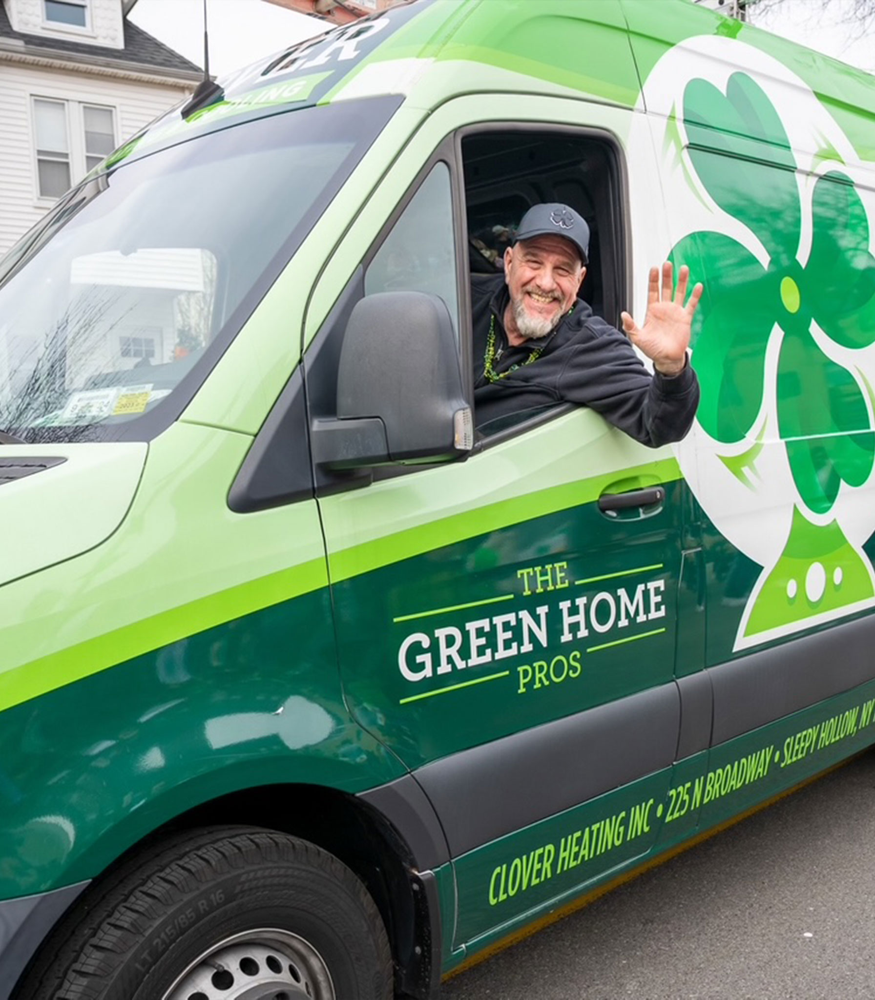 Man in green van labeled The Green Home Pros waving and smiling through the driver's window.