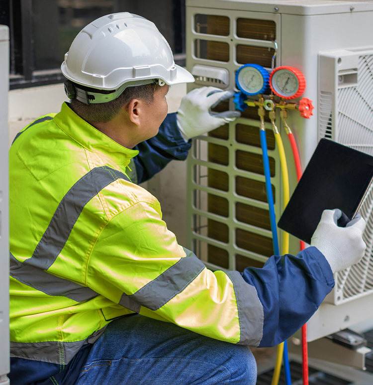 Technician inspecting HVAC system with gauges and clipboard.