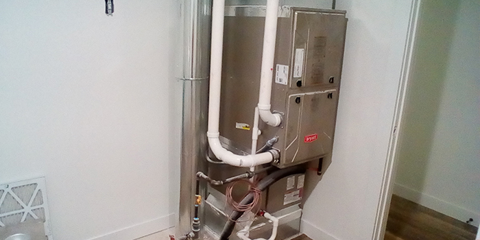 HVAC system installed in a utility room with piping and ductwork visible.