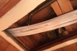 Exposed pipes and HVAC ducts in a ceiling under renovation.