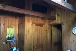 Wood-paneled room with doors, trophies on a shelf, and a hockey stick leaning against the wall.