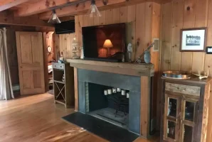 Cozy rustic living room with wooden walls, a fireplace, and vintage decor.