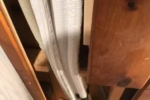 Air conditioning pipes and cables secured inside a wooden wall frame.