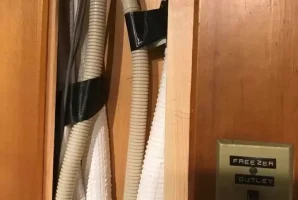 Hidden ductwork behind wooden panel with a freezer outlet switch nearby.