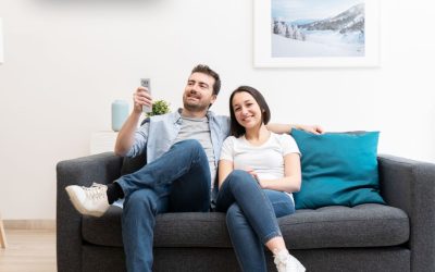 Couple relaxing on sofa under air conditioner in modern living room.