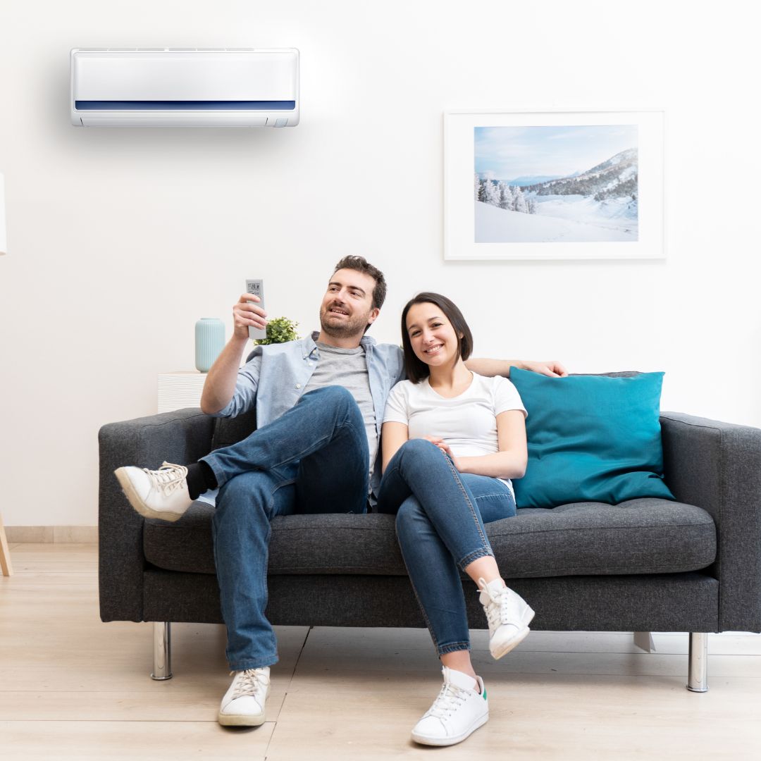 Couple relaxing on sofa under air conditioner in modern living room.