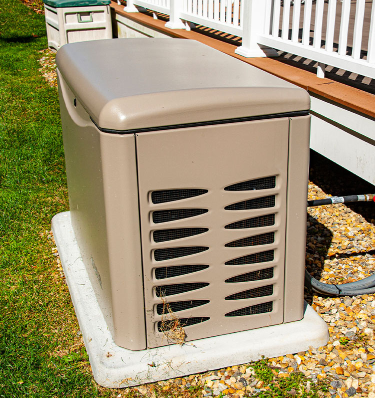 Outdoor home generator on concrete slab next to a porch, surrounded by grass and pebbles.