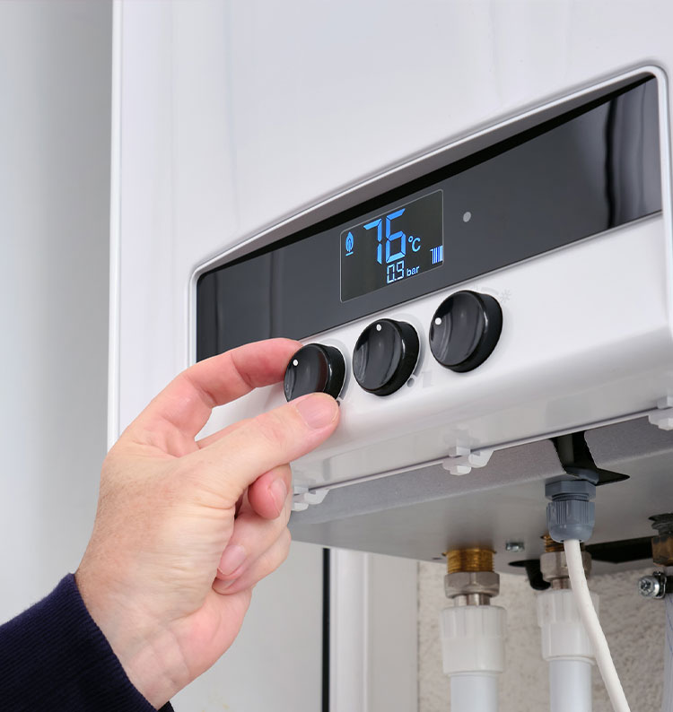 Hand adjusting temperature knob on a digital water heater display showing 75°C.