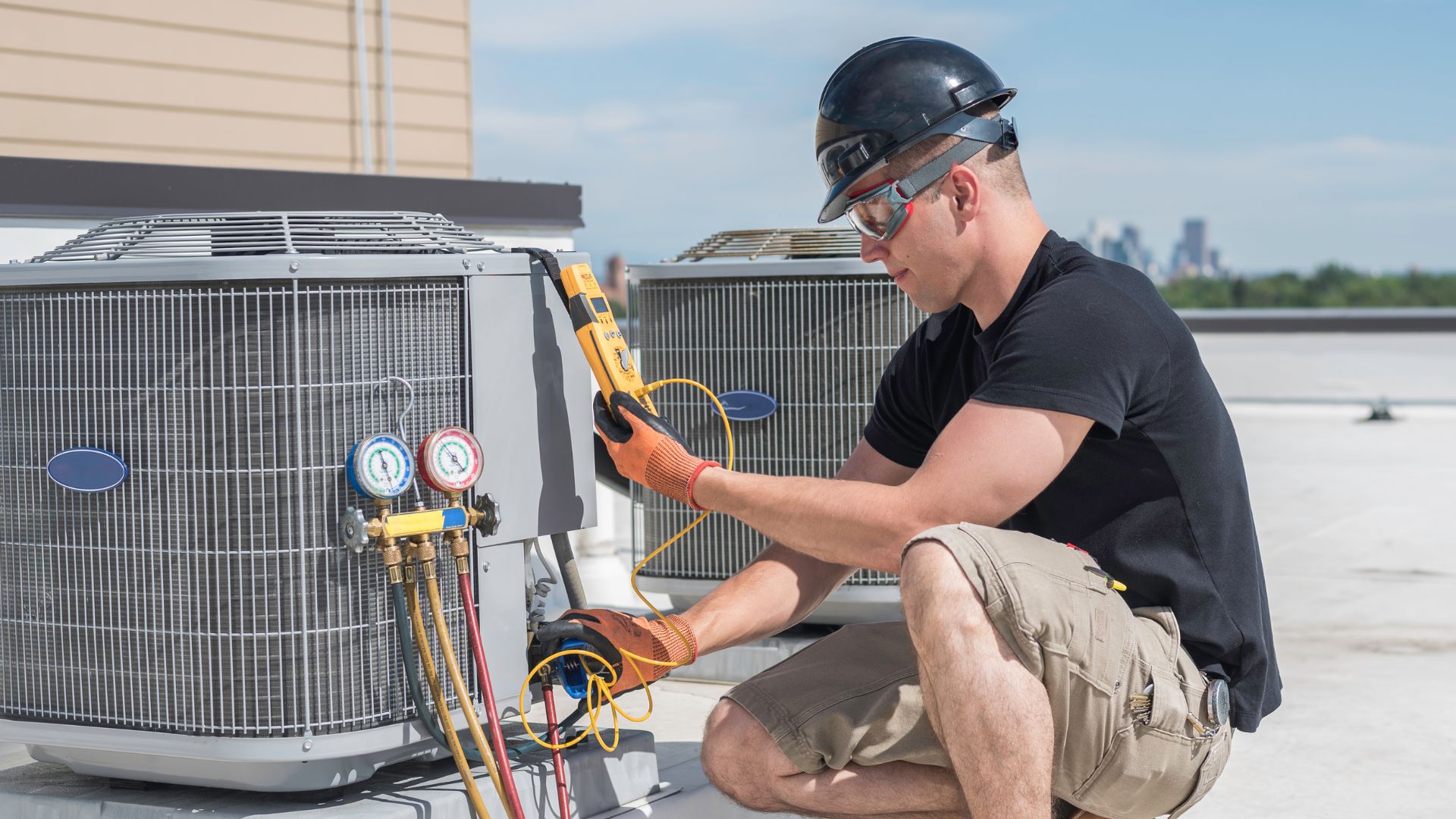 Technician servicing rooftop HVAC unit with gauges and tools.