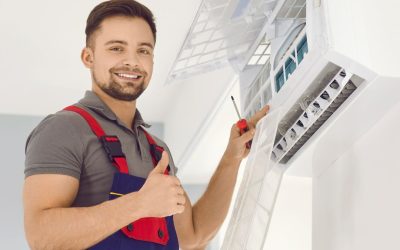 Technician smiling, repairing air conditioning unit with thumbs up.