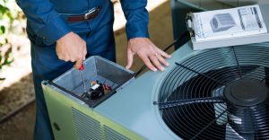 Technician repairing an outdoor air conditioning unit with tools and manual.