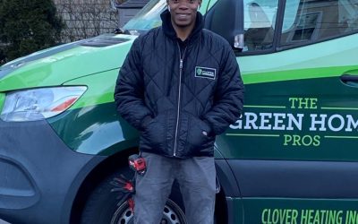 A man in a Clover Heating jacket stands in front of a branded company van.