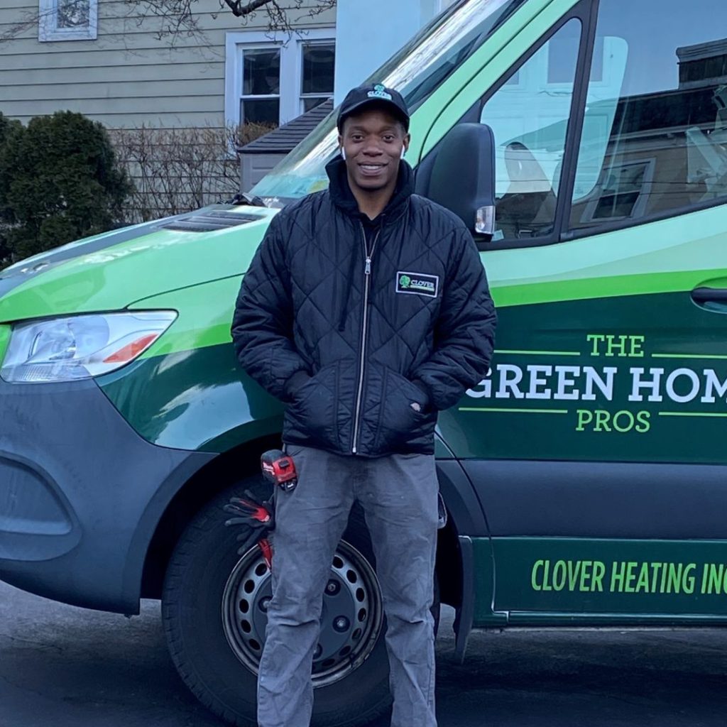 A man in a Clover Heating jacket stands in front of a branded company van.