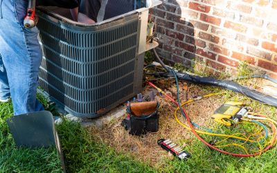 HVAC technician repairing outdoor air conditioning unit with gauges during AC repair and maintenance service