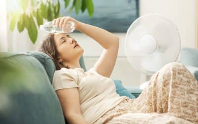 Young woman sitting on the couch at home, suffering from the heat and a poorly maintained AC.