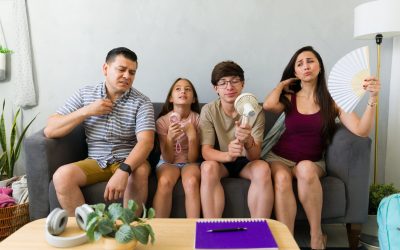Uncomfortable family uses fans indoors during a summer heat wave, needing AC repair or cooling tips.