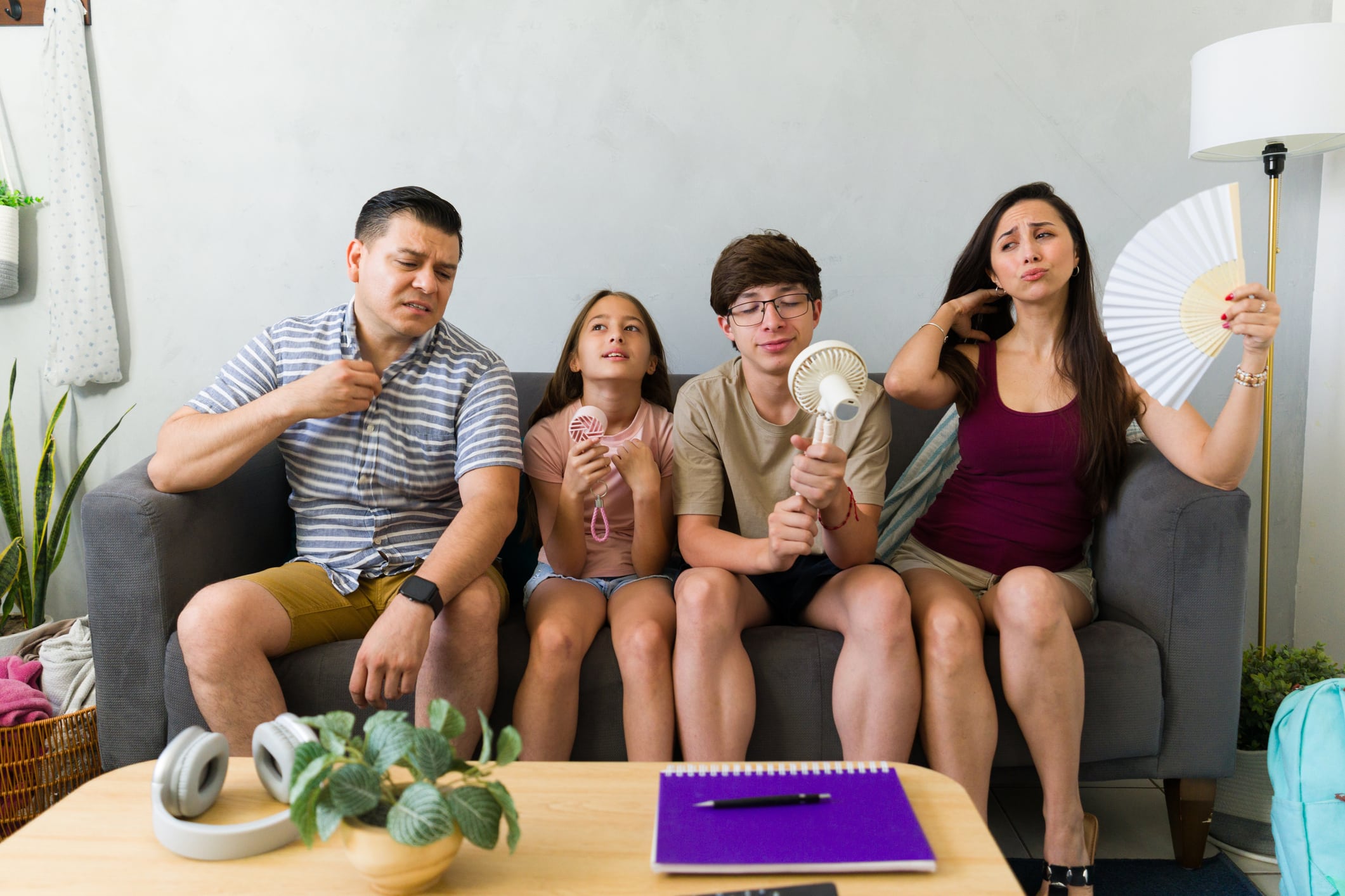Uncomfortable family uses fans indoors during a summer heat wave, needing AC repair or cooling tips.