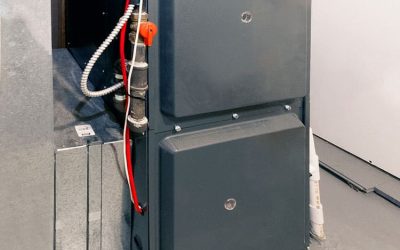Home furnace unit installation in a basement utility room with ductwork and wiring visible.