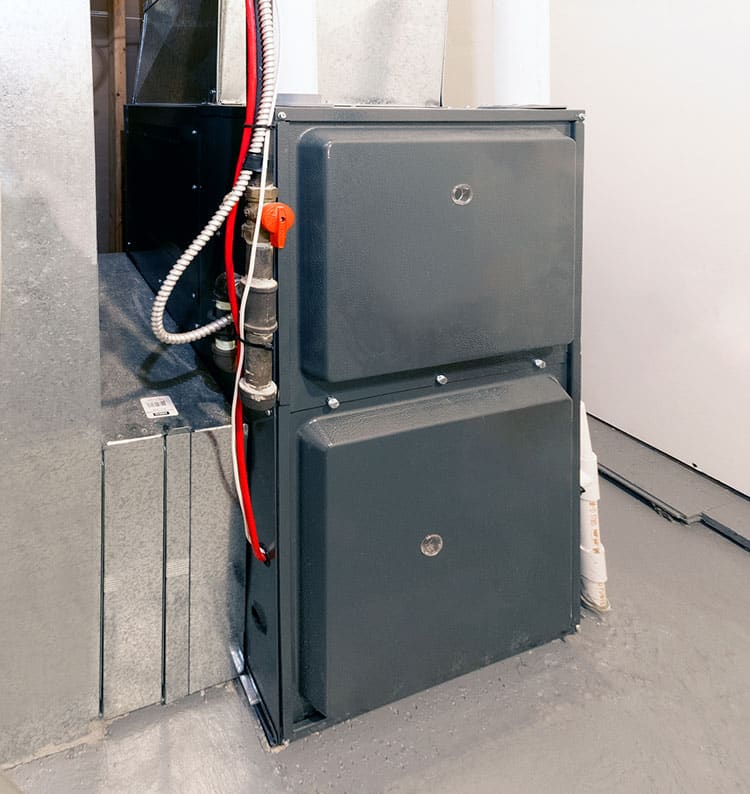 Home furnace unit installation in a basement utility room with ductwork and wiring visible.