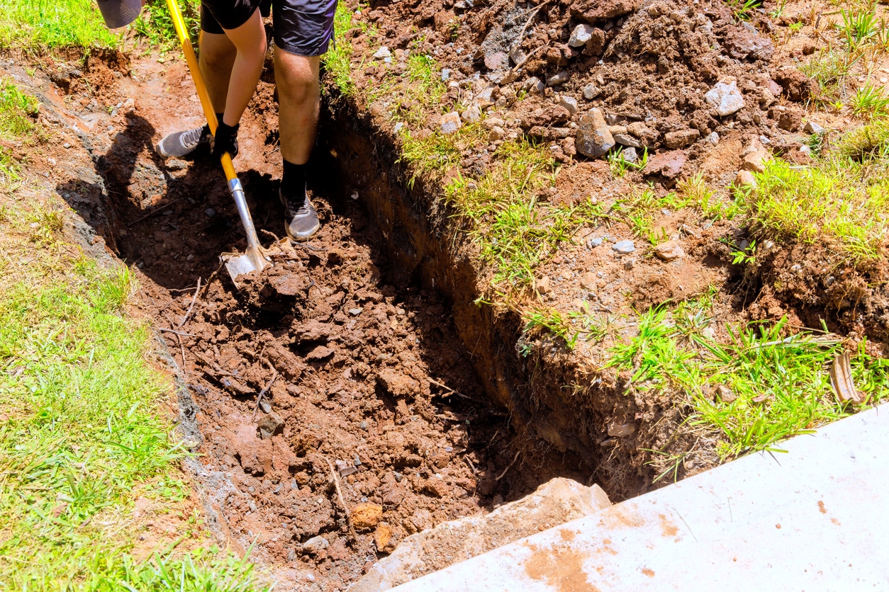 Crew digging a trench for a geothermal ground loop installation in a Westchester County backyard.